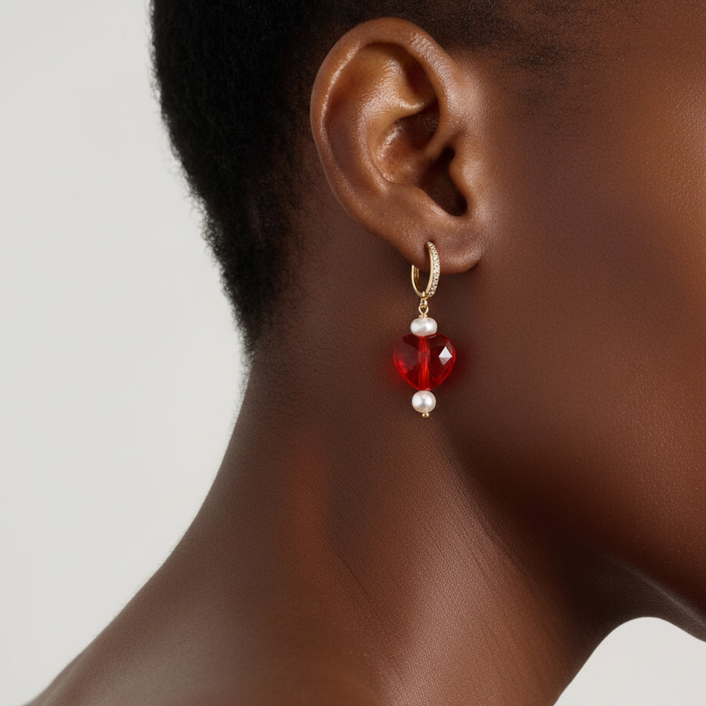 Close-up of an ear wearing a red and white earring against a neutral background