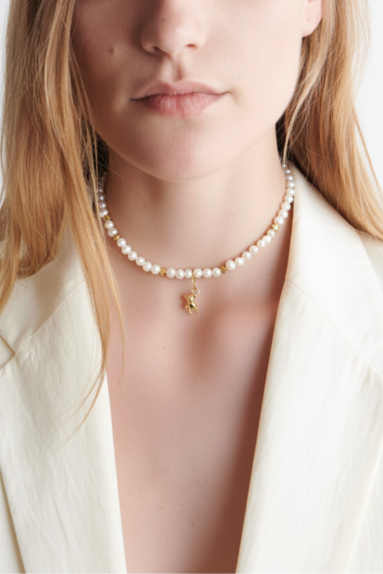 Pearl necklace with a gold pendant worn by a person against a white background