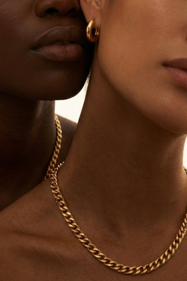 Two women wearing gold chain necklaces against a warm background